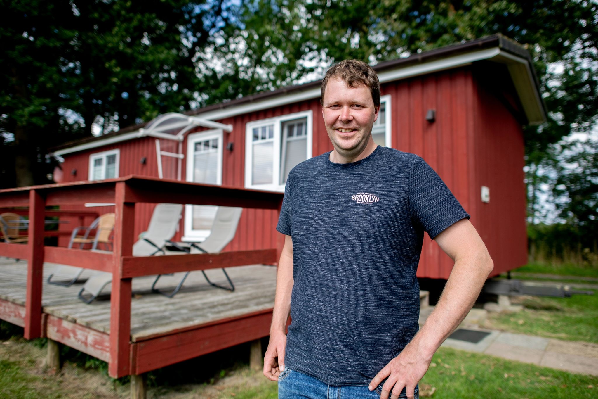 Markus Mushardt, Landwirt und Betreiber eines Ferienhofs, steht vor einem Tiny House aus Holz.