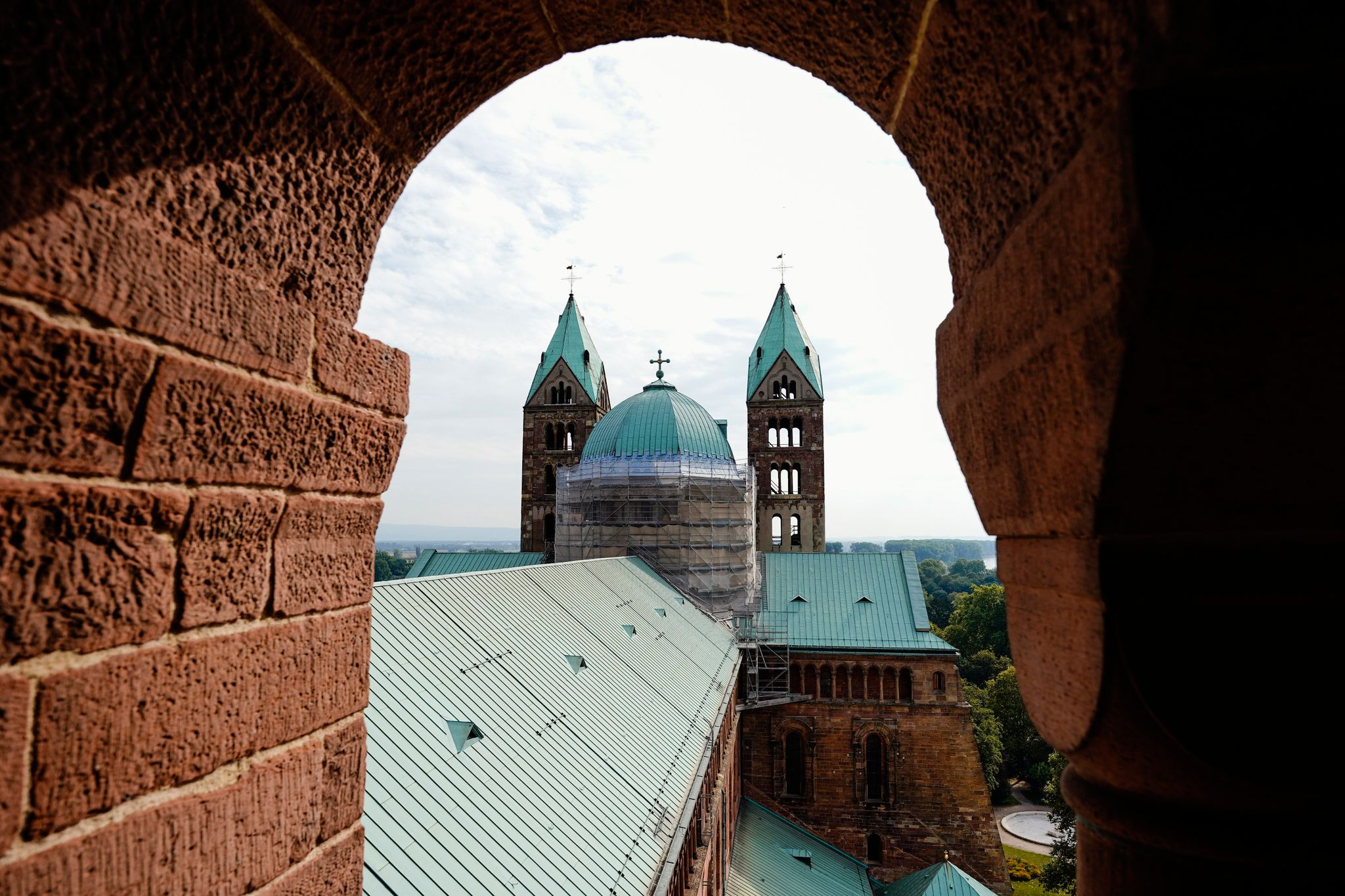 Durch ein Fenster sieht man die zwei östlichen Kirchtürme sowie das Dach des Mittelschiffs des Doms zu Speyer.