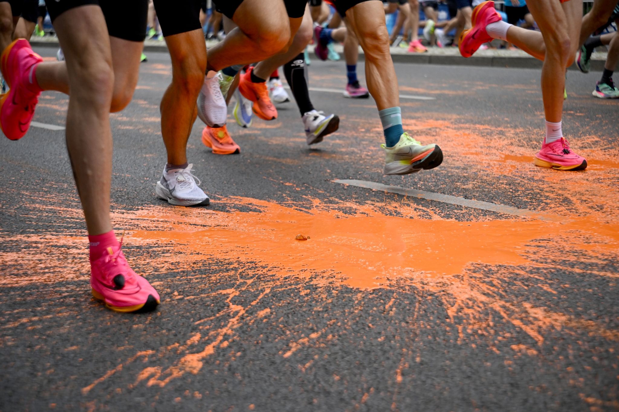Die Läufer laufen über die von den Klimaaktivisten auf die Strecke geschüttete Farbe.
