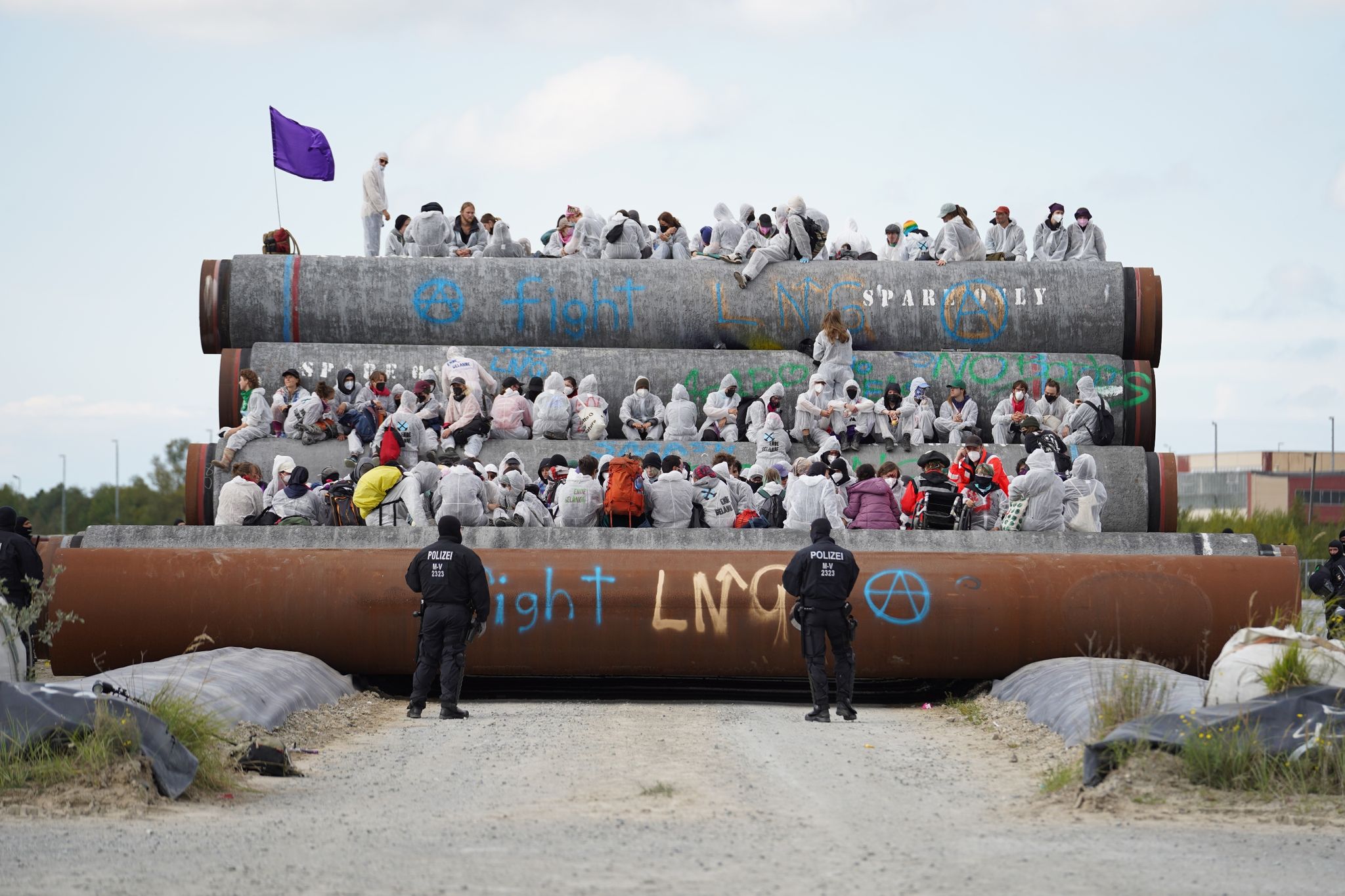 Teilnehmer des Protests sitzen auf liegenden Rohren für die geplante Pipeline.