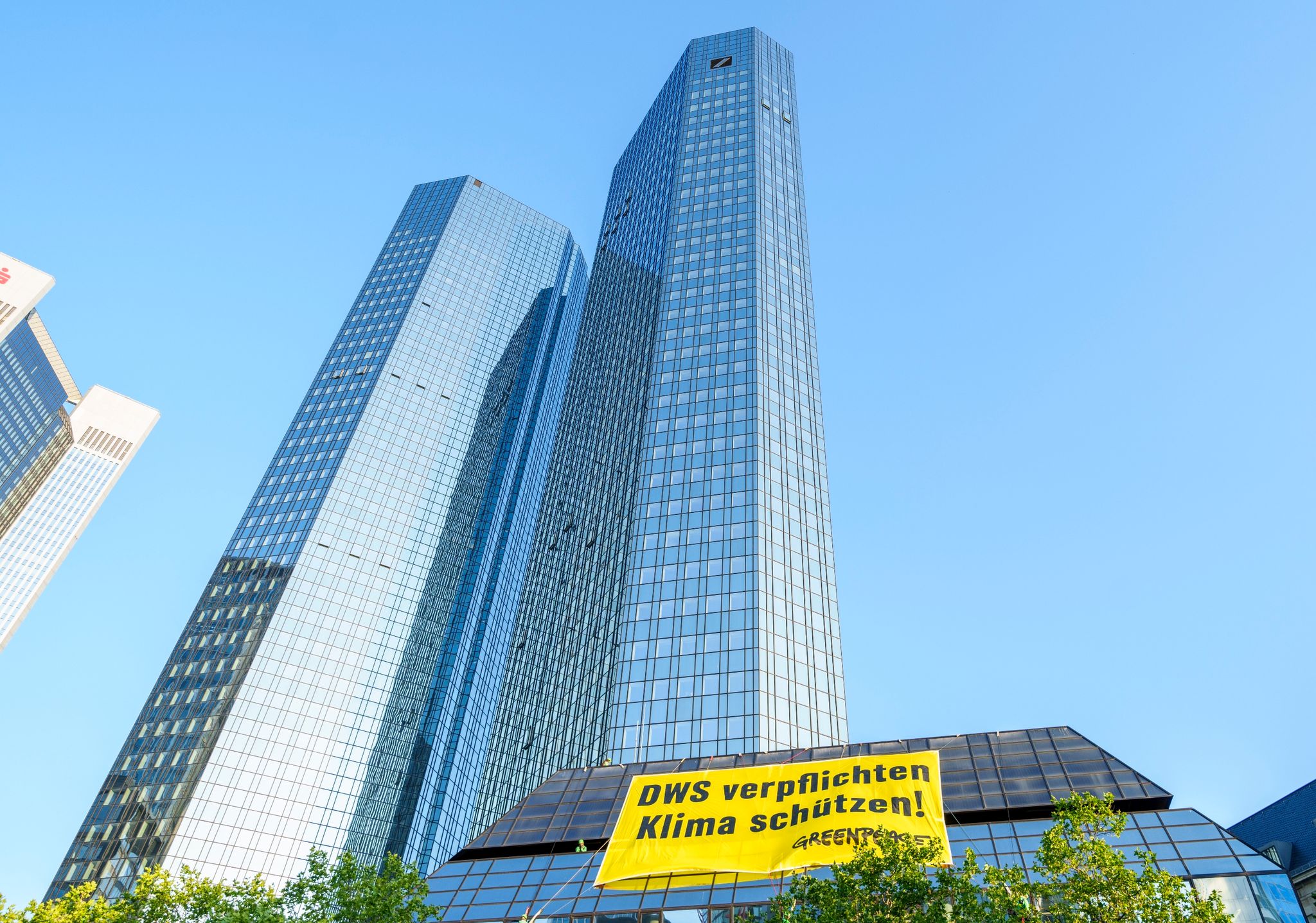 Ein Greenpeace-Banner „DWS verpflichten Klima schützen!“ hängt an einem Gebäude der Deutschen Bank.