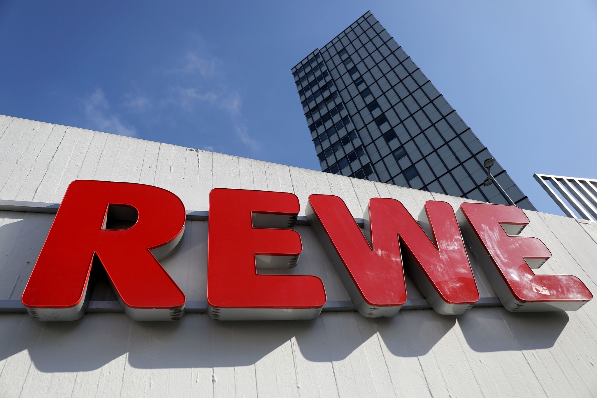 Der Schriftzug «Rewe» hängt an einem Supermarkt.