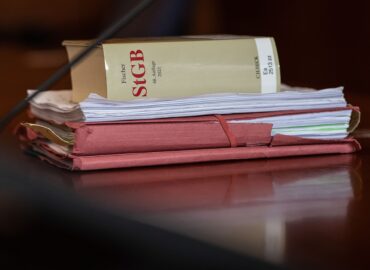Das Strafgesetzbuch und Akten liegen in einem Gericht auf dem Tisch.